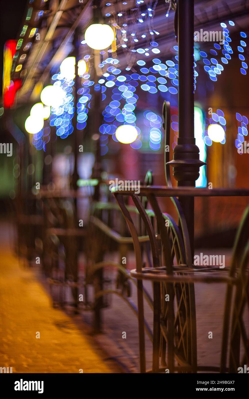 Fences and blurred night lights decorations of the bar on background. Christmas time in the city. Abstract background Stock Photo