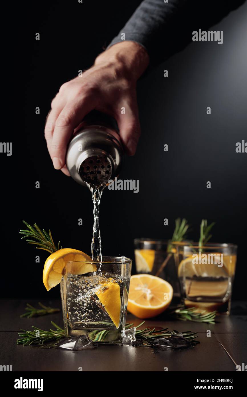 Cocktail Gin and Tonic with lemon and rosemary. The bartender pours a