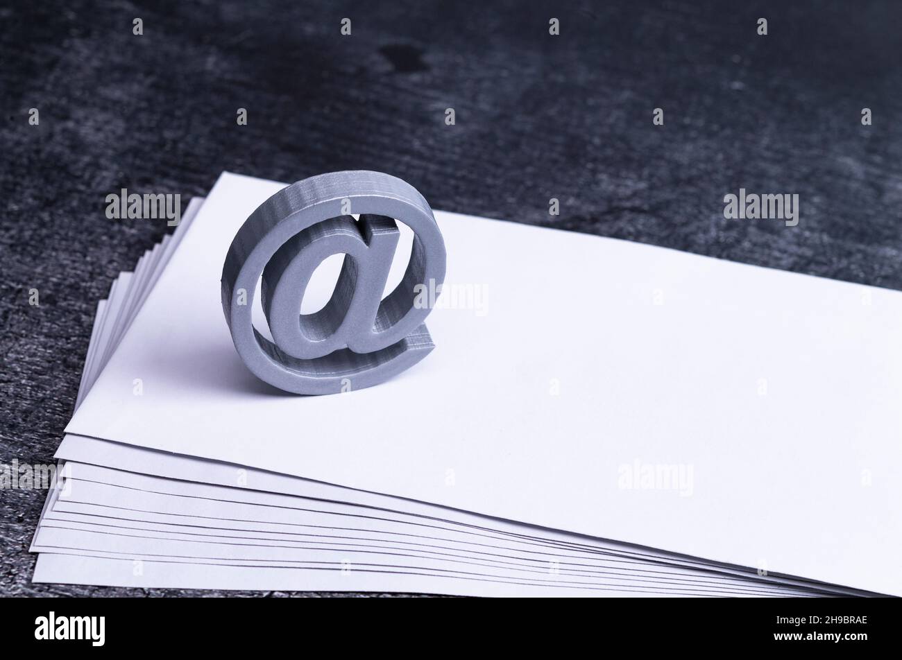 The photo shows an AT sign on a stack of envelopes Stock Photo