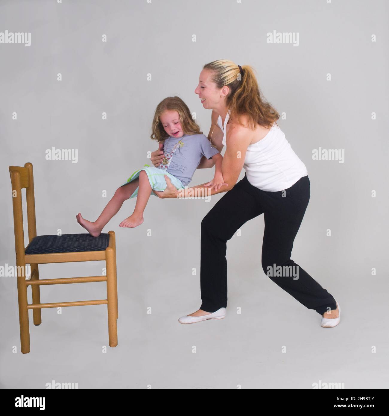 Mother catches daughter of 3 as she falls of a chair Stock Photo