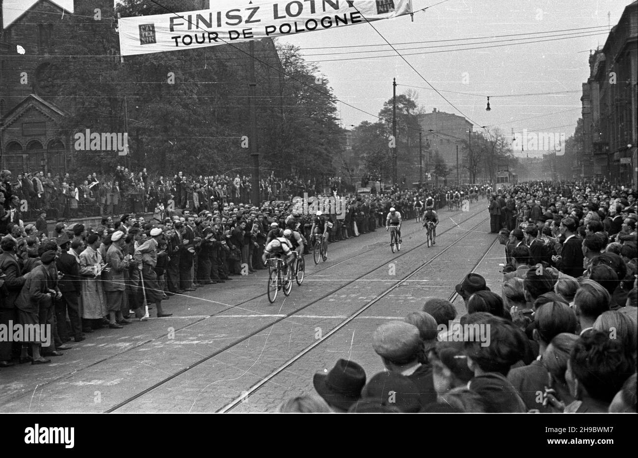 Katowice, 1947-09-25. Pierwszy powojenny Wyœcig Kolarski Dooko³a Polski (VI Tour de Pologne) na trasie Kraków–Warszawa. Nz. etap pierwszy: Kraków-Bytom; finisz lotny na ul. Warszawskiej w Katowicach. Kolarze (m.in Lucjan Pietraszewski, Andrzej Grynkiewicz) przeje¿d¿aj¹ przez liniê pomiaru czasu. W tle koœció³ ewangelicki z XIX wieku. bk/mgs PAP Bytom, Sept. 25, 1947. The first after the war Cycling Race around Poland (VI Tour de Pologne) from Cracow to Warsaw. Pictured: finish of the first stage Cracow-Bytom. bk/mgs PAP Stock Photo