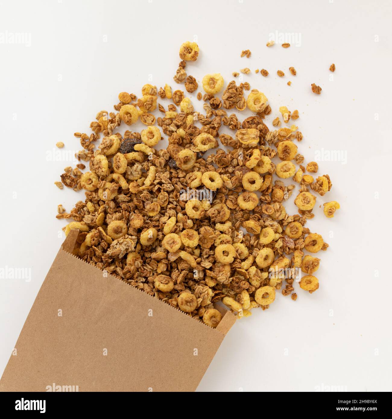 crunchy granola for breakfast, tasty granola poured out of paper bag isolated on white background, concept healthy food Stock Photo