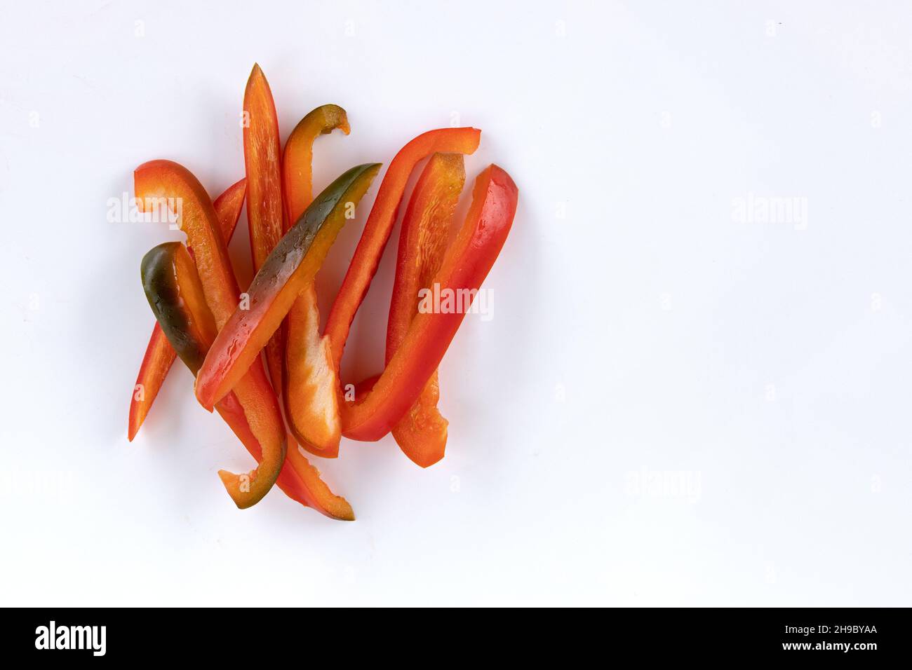 red sweet bell pepper sliced strips with copy space for text isolated on white background, fresh vegetables, top view Stock Photo
