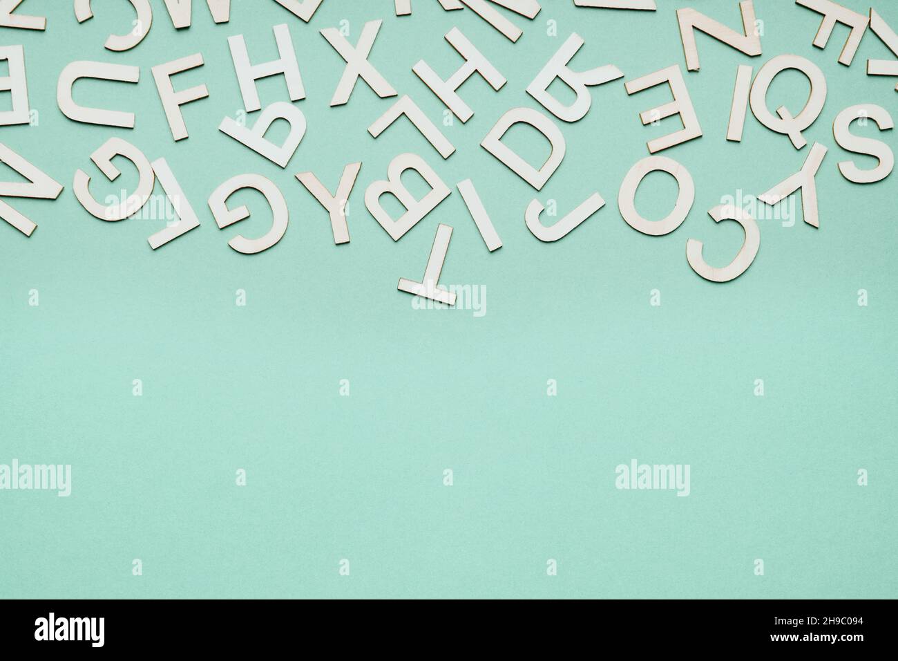 jumble of wooden letters falling down on blue paper background Stock Photo