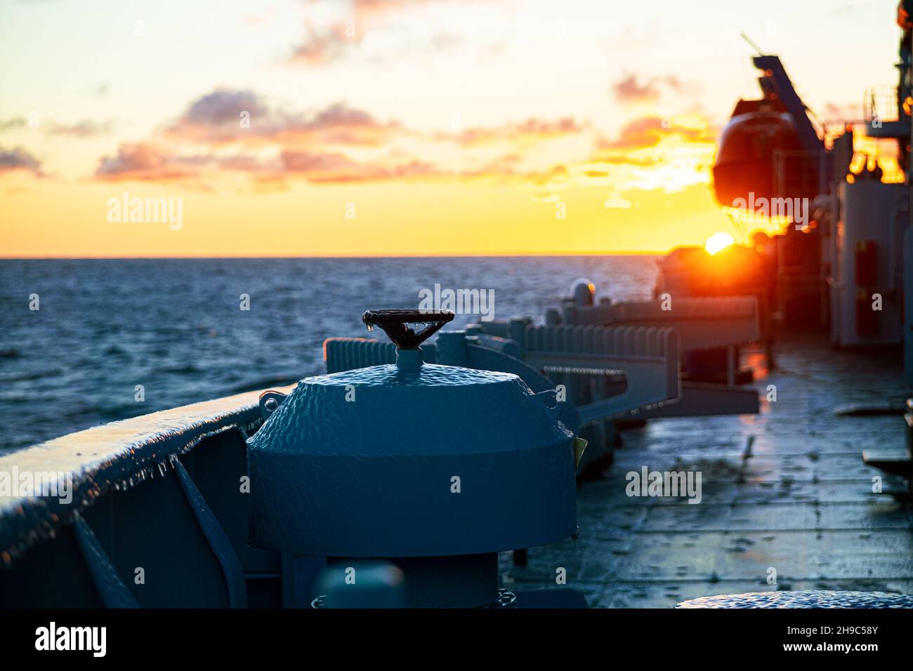 Arctic climate, details of the ventilation box at the side of the ship, covered with an ice crust, against the background of a colorful rising sun Stock Photo