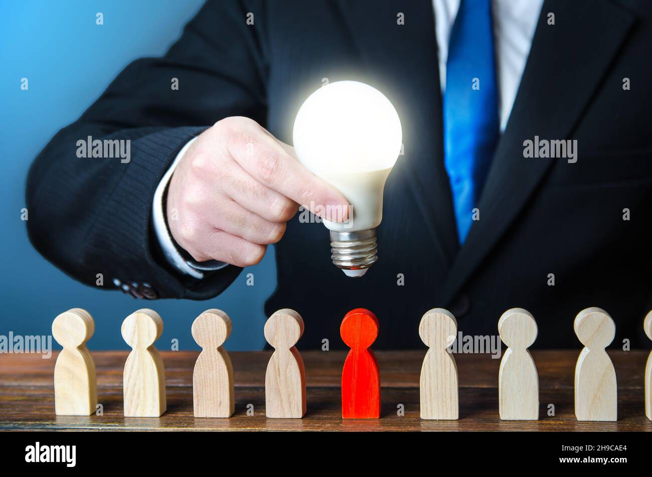 Businessman holds idea light bulb over employee. Search for recruiting talent. Professional job candidates. Employment of talented workers. Identifyin Stock Photo
