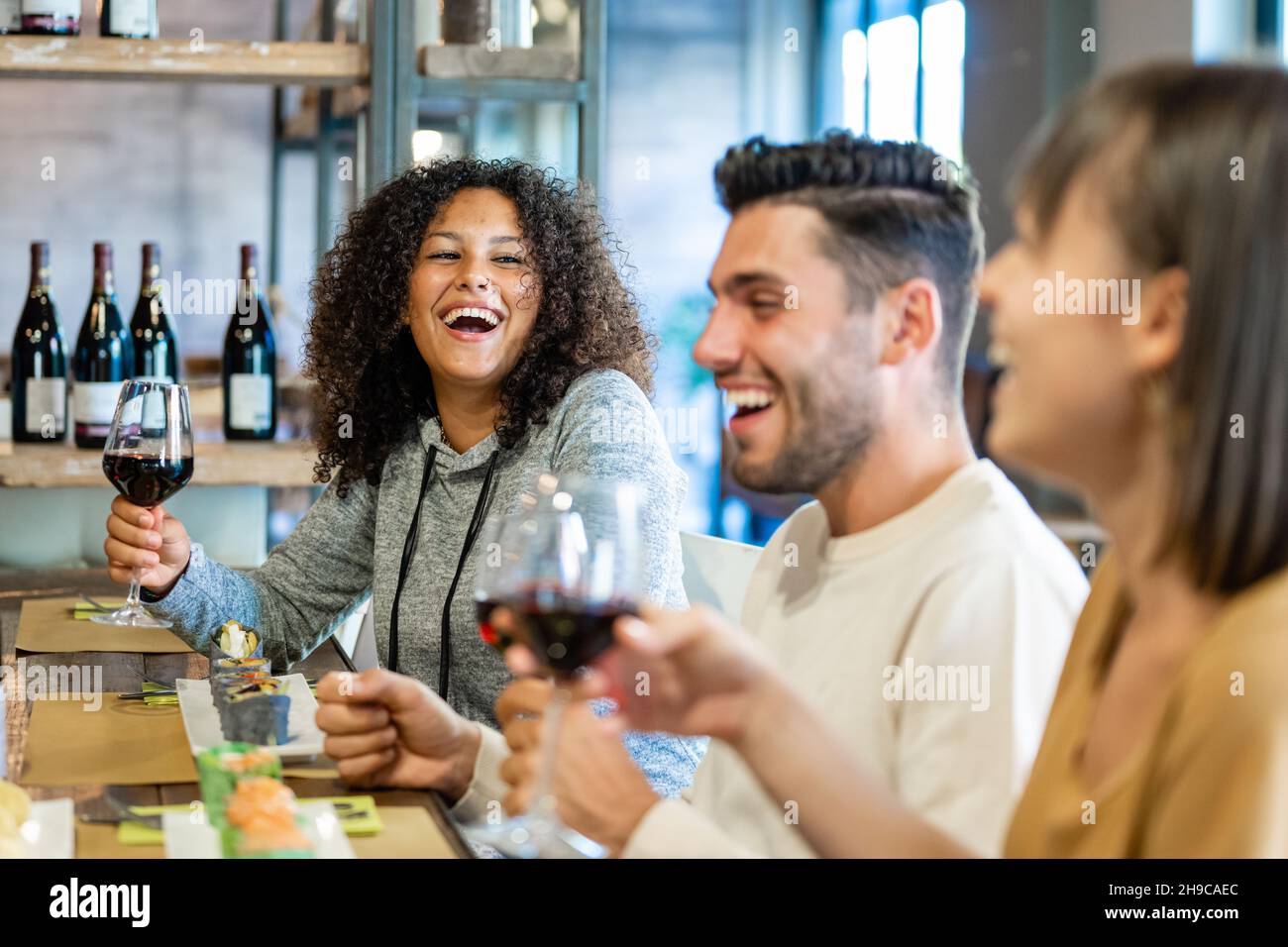Group of young people having lunch at restaurant, millennials having fun together on a day of celebration, toasting with glasses of red wine Stock Photo