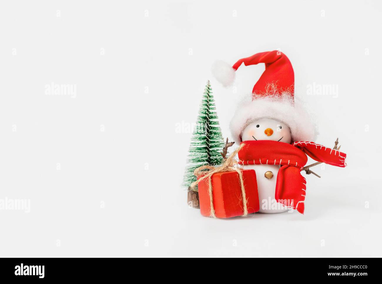 Happy snowman with a gift near the Christmas tree on the white background Stock Photo