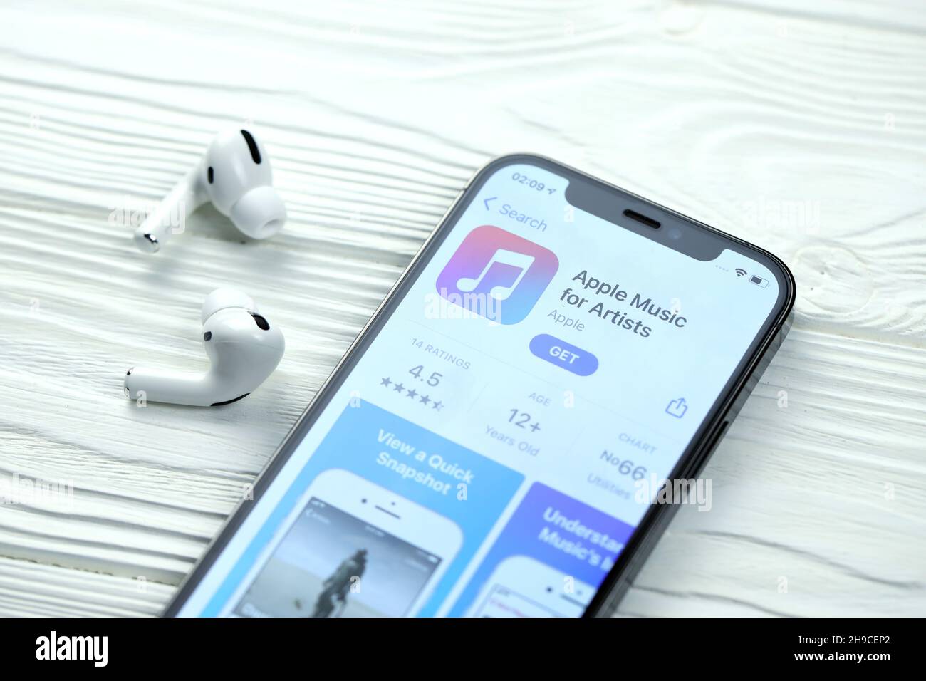KHARKOV, UKRAINE - MARCH 5, 2021: Apple music for artists icon and application from App store on iPhone 12 pro display screen with airpods pro on whit Stock Photo