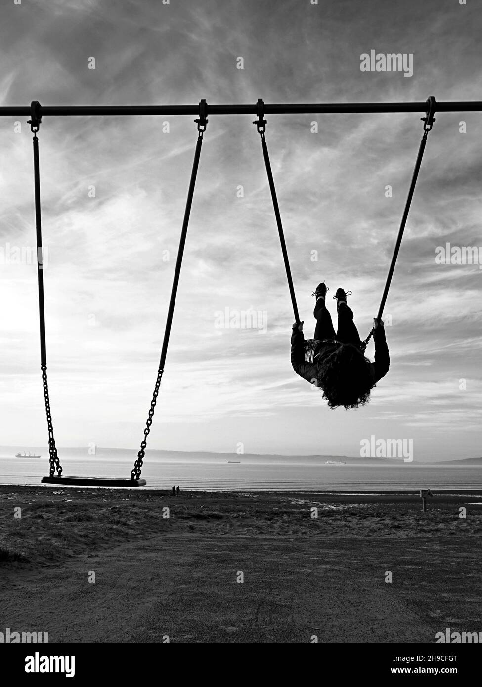 Silhouette of a girl on a swing. High contrast black and white photograph Stock Photo