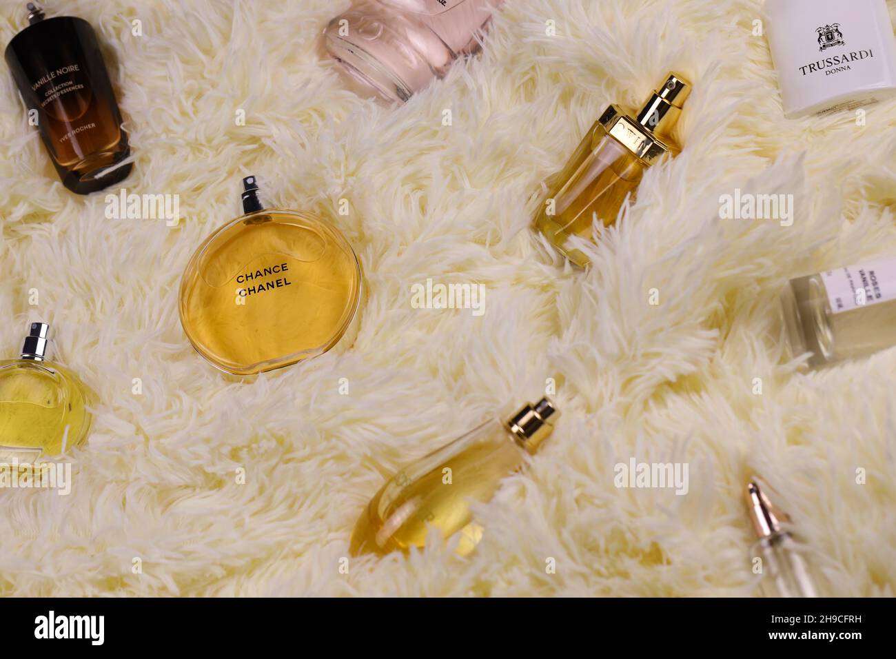 KHARKOV, UKRAINE - JANUARY 12, 2021: Many perfume bottles with famous brand names lies on fluffy beige plaid. Luxury elite perfume set Stock Photo