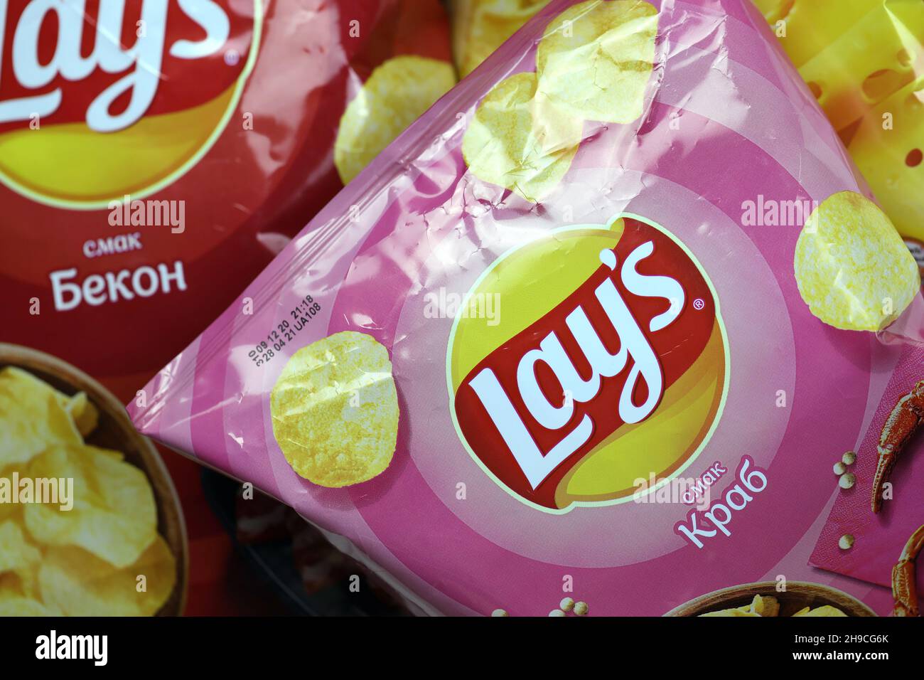 KHARKOV, UKRAINE - JANUARY 3, 2021: Various flavoured of lay's potato chips on wooden background. Lay's has been owned by PepsiCo through Frito-Lay si Stock Photo