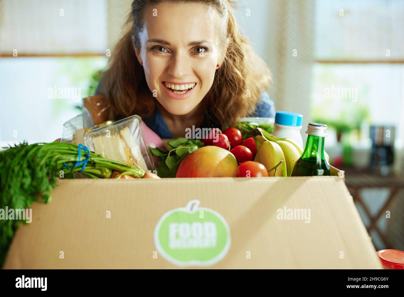 Food delivery. happy young housewife with food box in the kitchen Stock