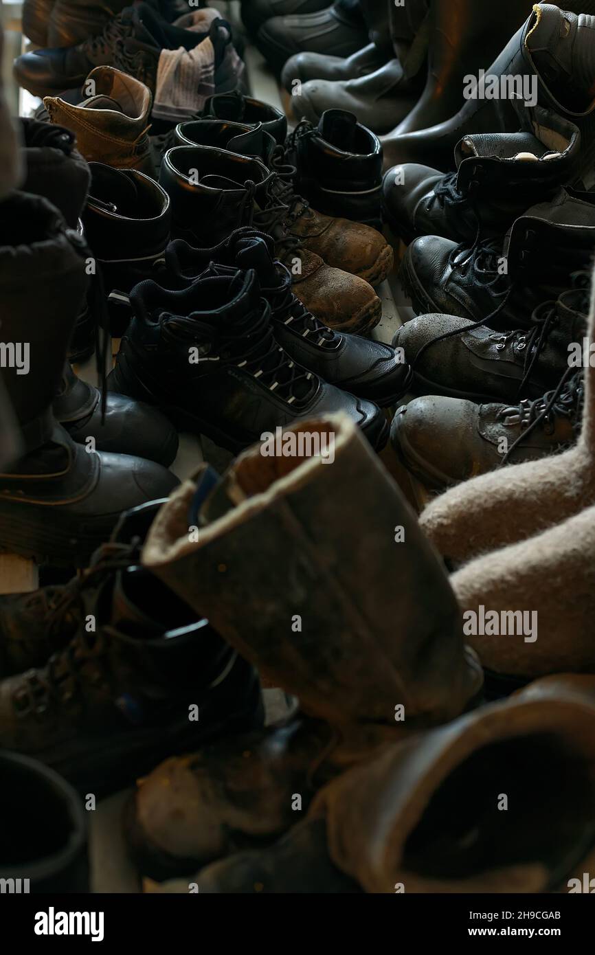 Many old work boots stand together. Old worn construction boots of