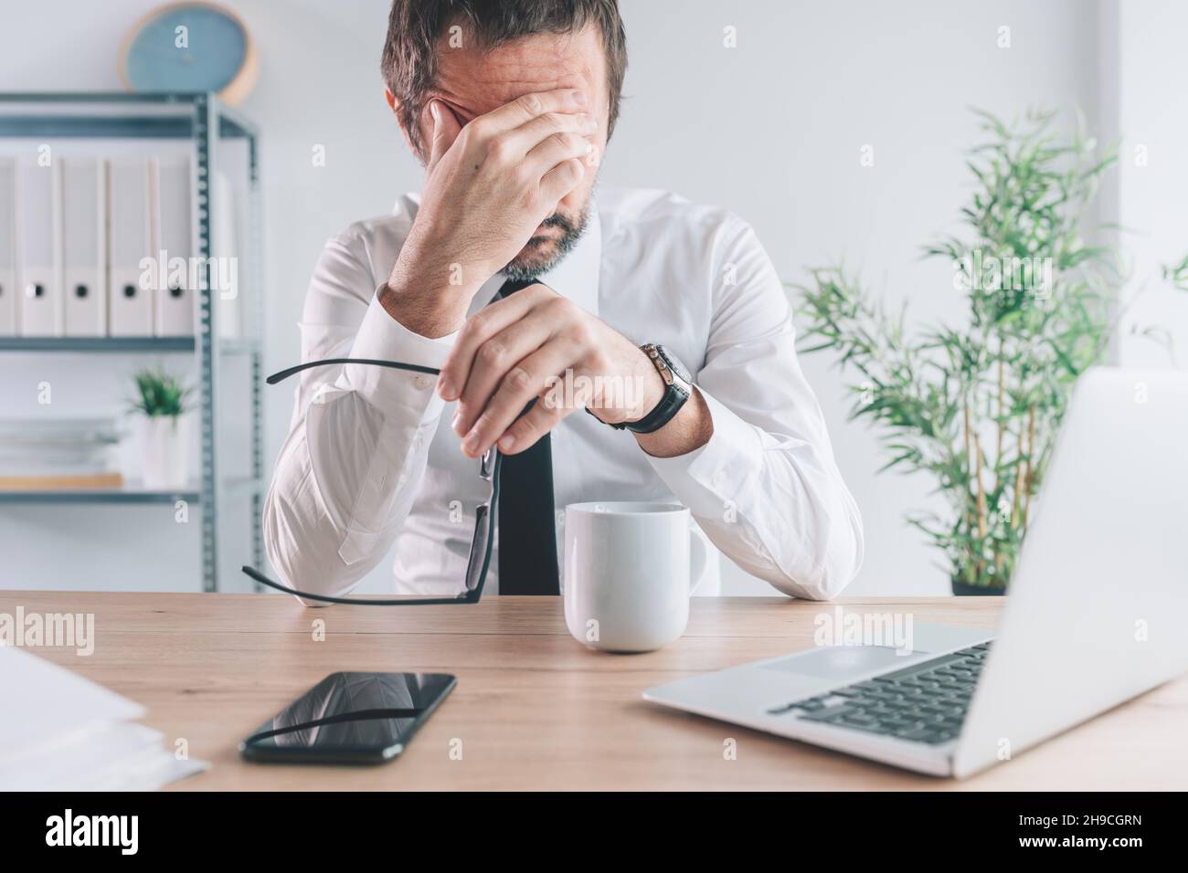 Businessman and entrepreneur realizing the big mistake he made, hand covering face in disbelief, selective focus Stock Photo