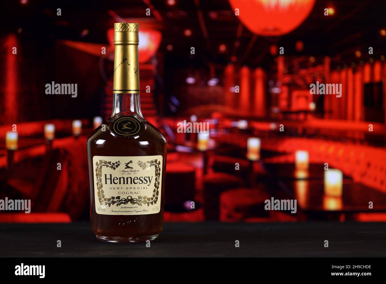 KHARKOV, UKRAINE - FEBRUARY 14, 2021: Hennessy very special cognac bottle on wooden table with red bar interior on background. Elite alcohol productio Stock Photo