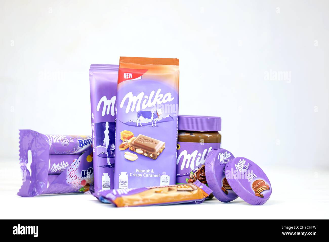 KHARKOV, UKRAINE - JULY 2, 2021: Milka chocolate products with classical lilac color wrapping design on white wooden table Stock Photo