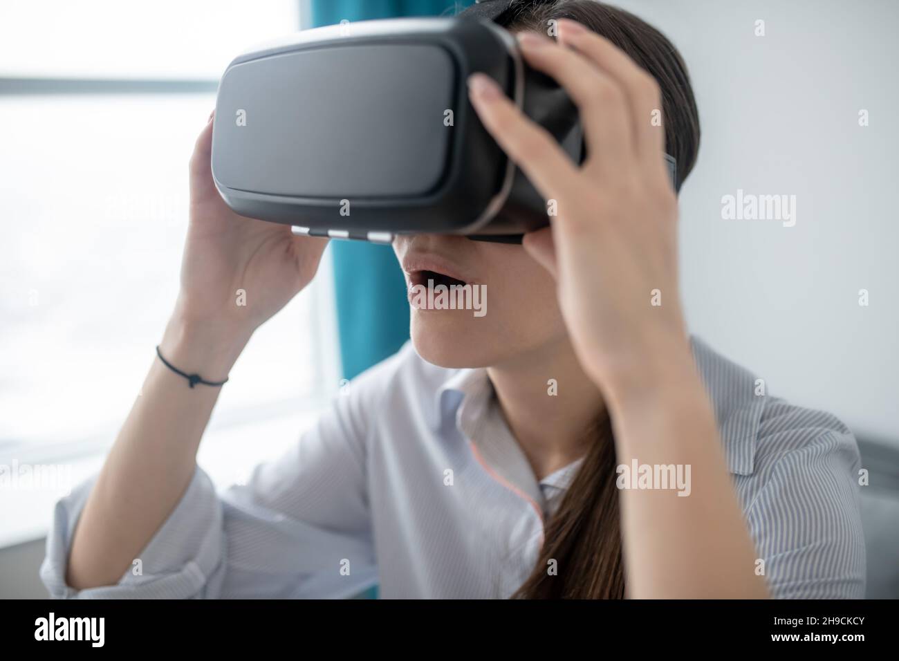 Open-mouthed young woman playing a 3D game Stock Photo