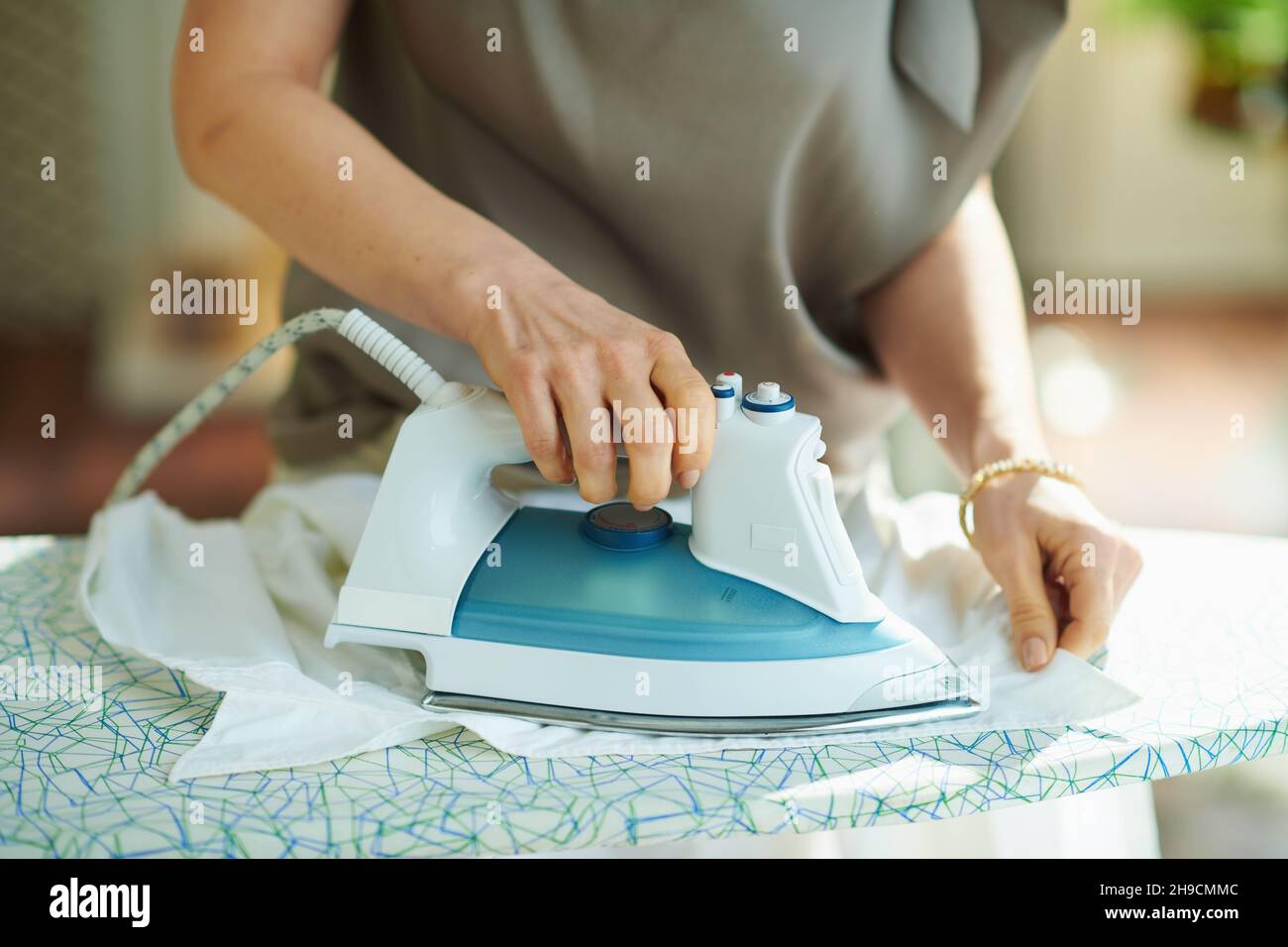 Closeup on woman in silk blouse and beige pants in the house in sunny
