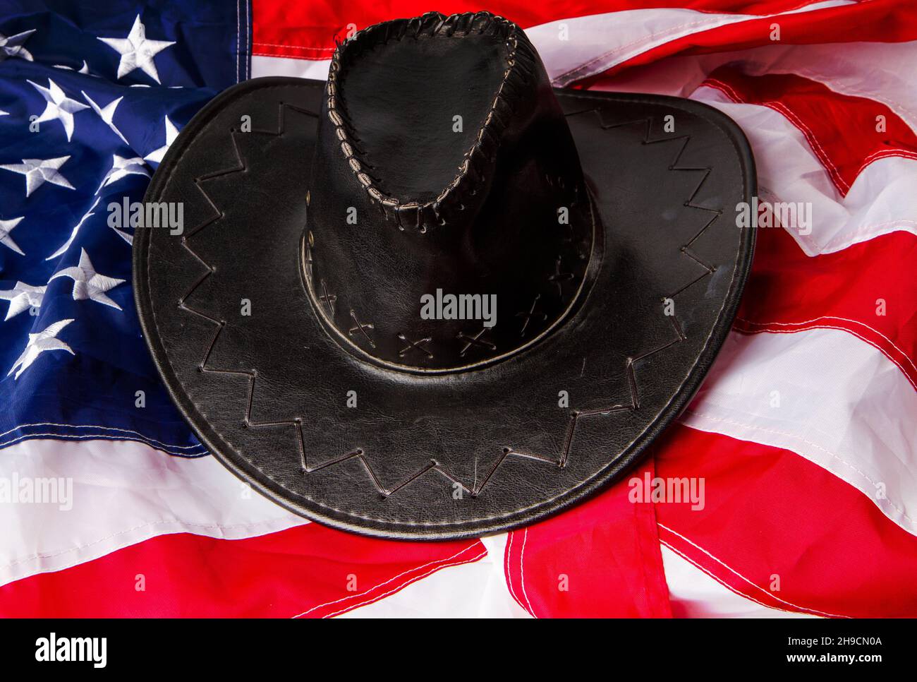 black classic wide-brimmed cowboy hats on the background of the flag of the united states of america Stock Photo