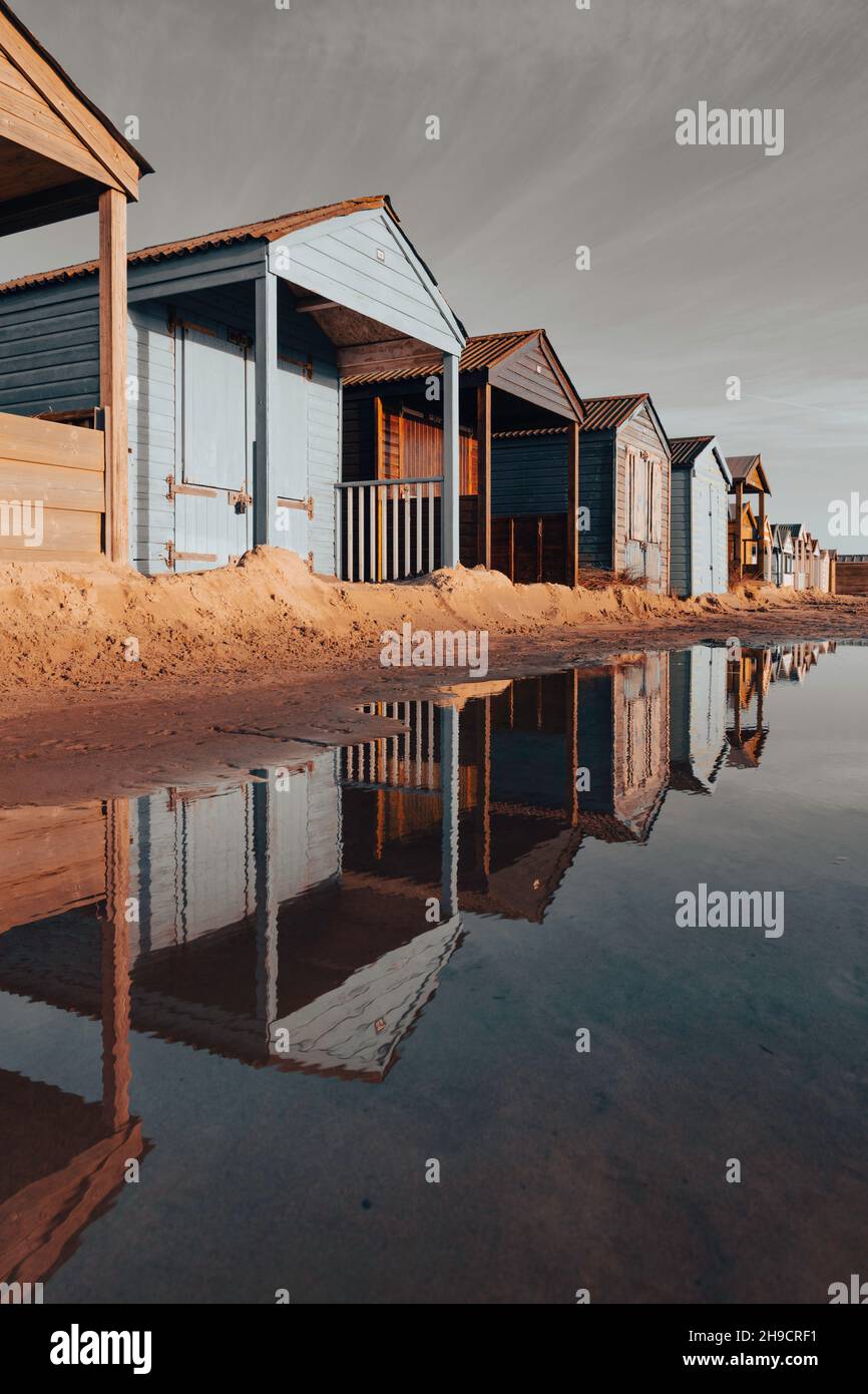 A row of beach huts reflected in a large puddle Stock Photo