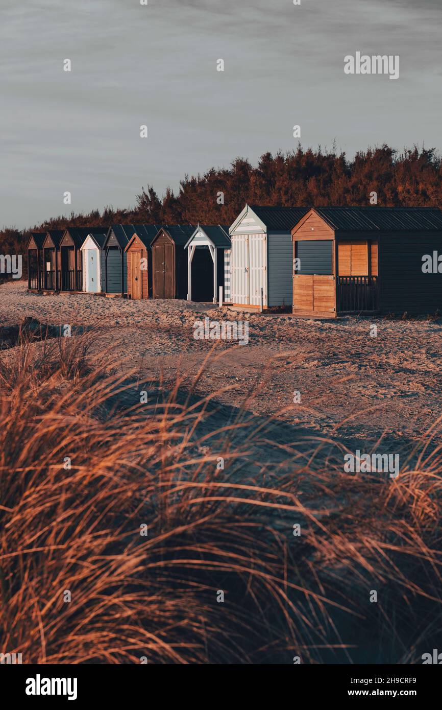Beach huts in a row beyond sand dunes Stock Photo