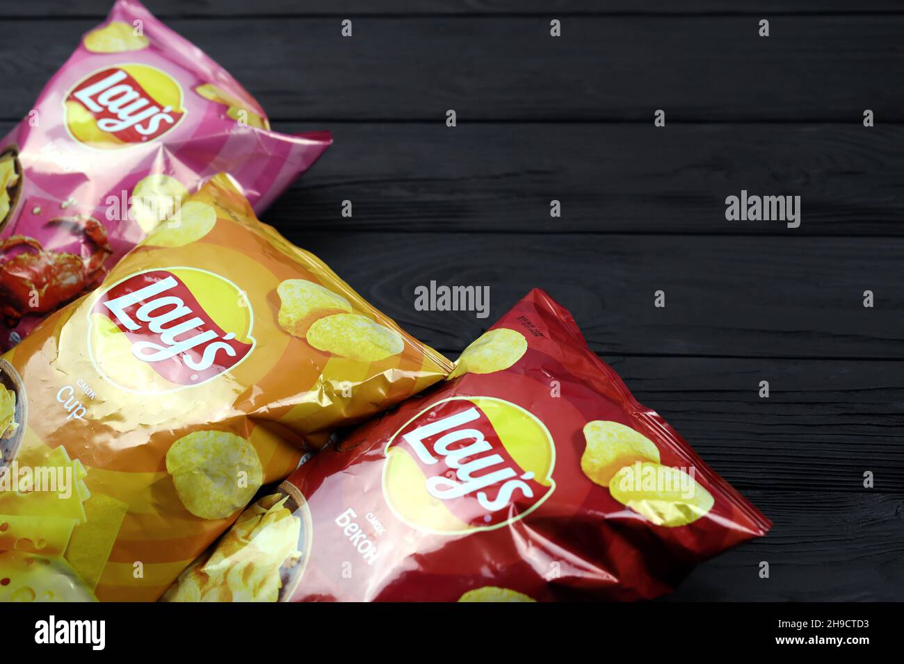KHARKOV, UKRAINE - JANUARY 3, 2021: Various flavoured of lay's potato chips on wooden background. Lay's has been owned by PepsiCo through Frito-Lay si Stock Photo