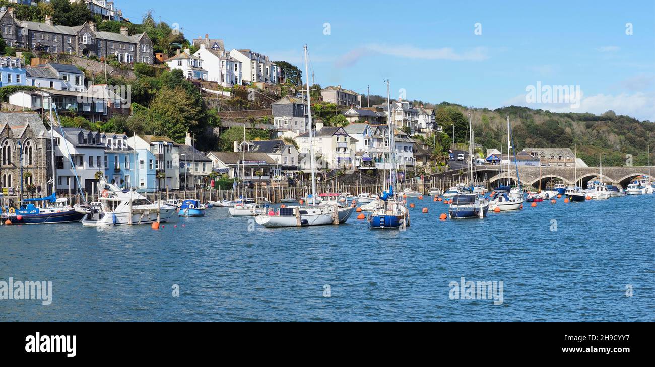 The harbour in Looe Cornwall showing the dwellings on the hills, surrounding the many moored boats on the water and the bridge Stock Photo