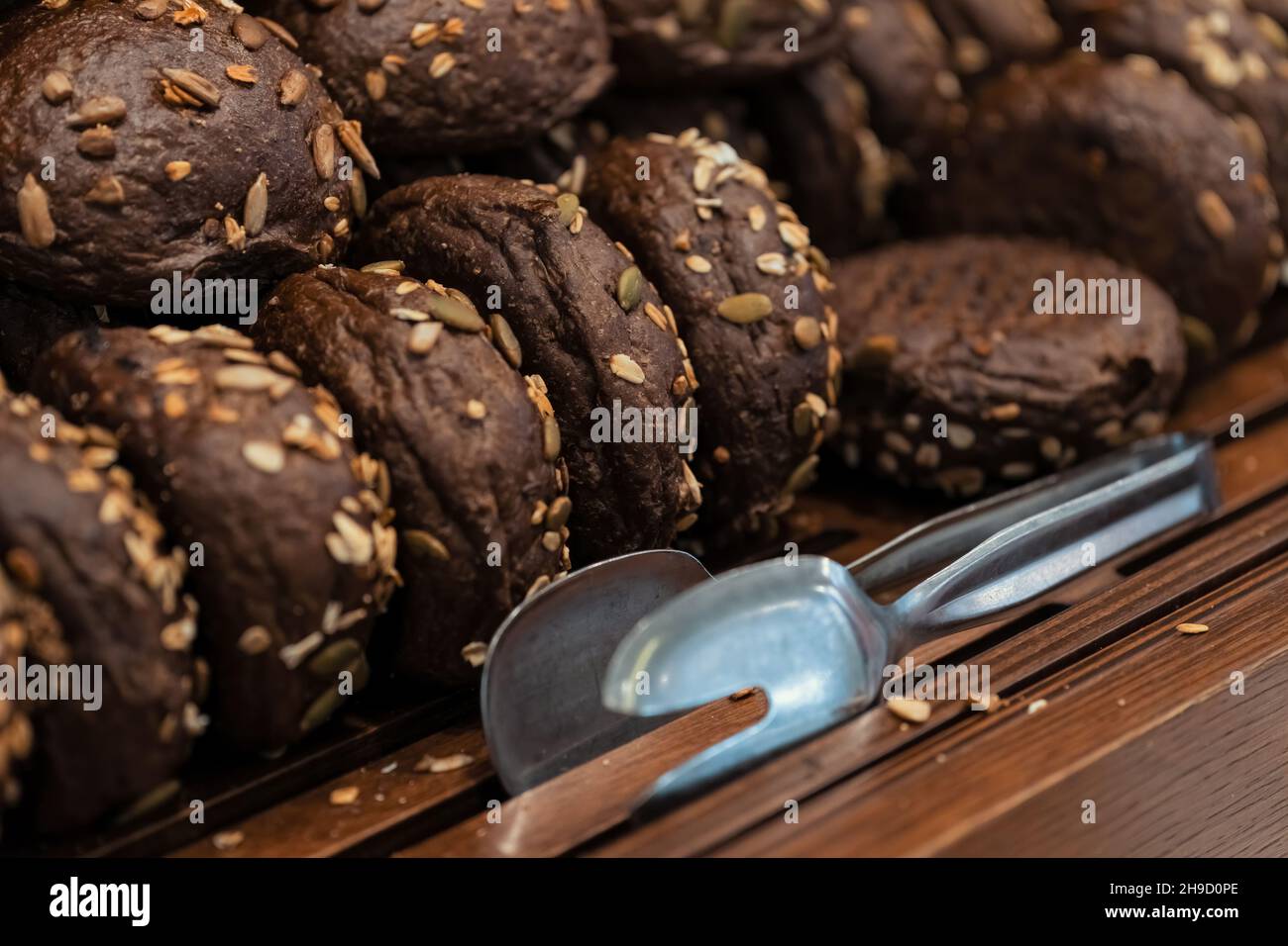 Close-up photo of rye buns with sunflower seedss in wooden trays at the hotel restaurant. Stock Photo
