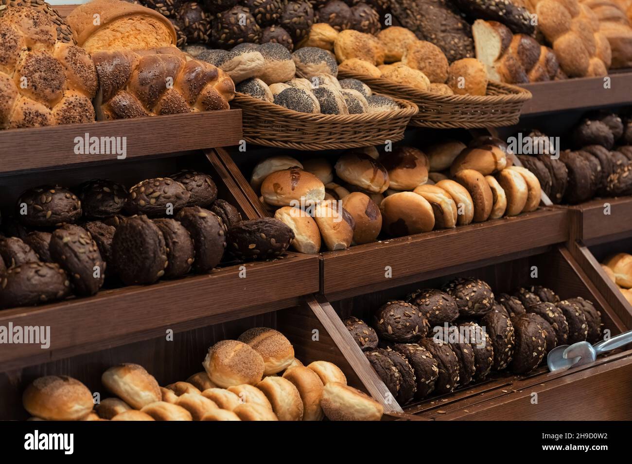 Breakfast lines of zopf or züpfe bread with sesames,  rye buns with sunflower seeds and white wheat buns with poppy seeds in wooden trays at the hotel Stock Photo