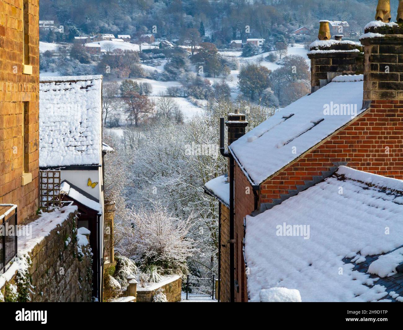Snow covered landscape with trees at Matlock Bath in the Derbyshire Peak District England UK with houses in the forreground. Stock Photo