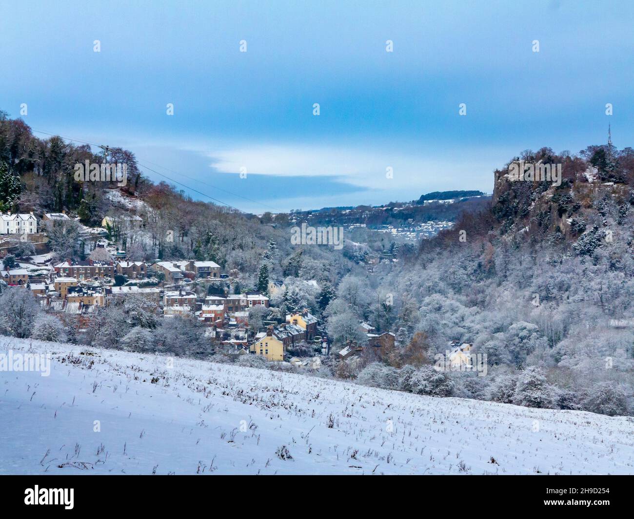 Snow covered landscape with trees at Matlock Bath in the Derbyshire Peak District England UK with High Tor visible in the distance. Stock Photo