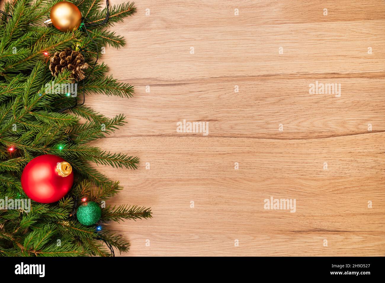 Christmas background with fir branches baubles and lights on wooden board Stock Photo