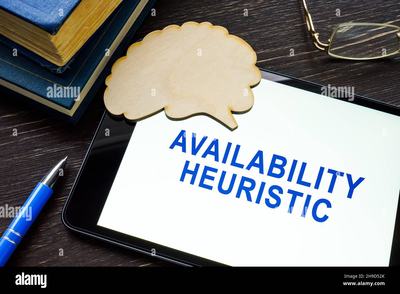 Tablet with words availability heuristic and brain shape. Stock Photo