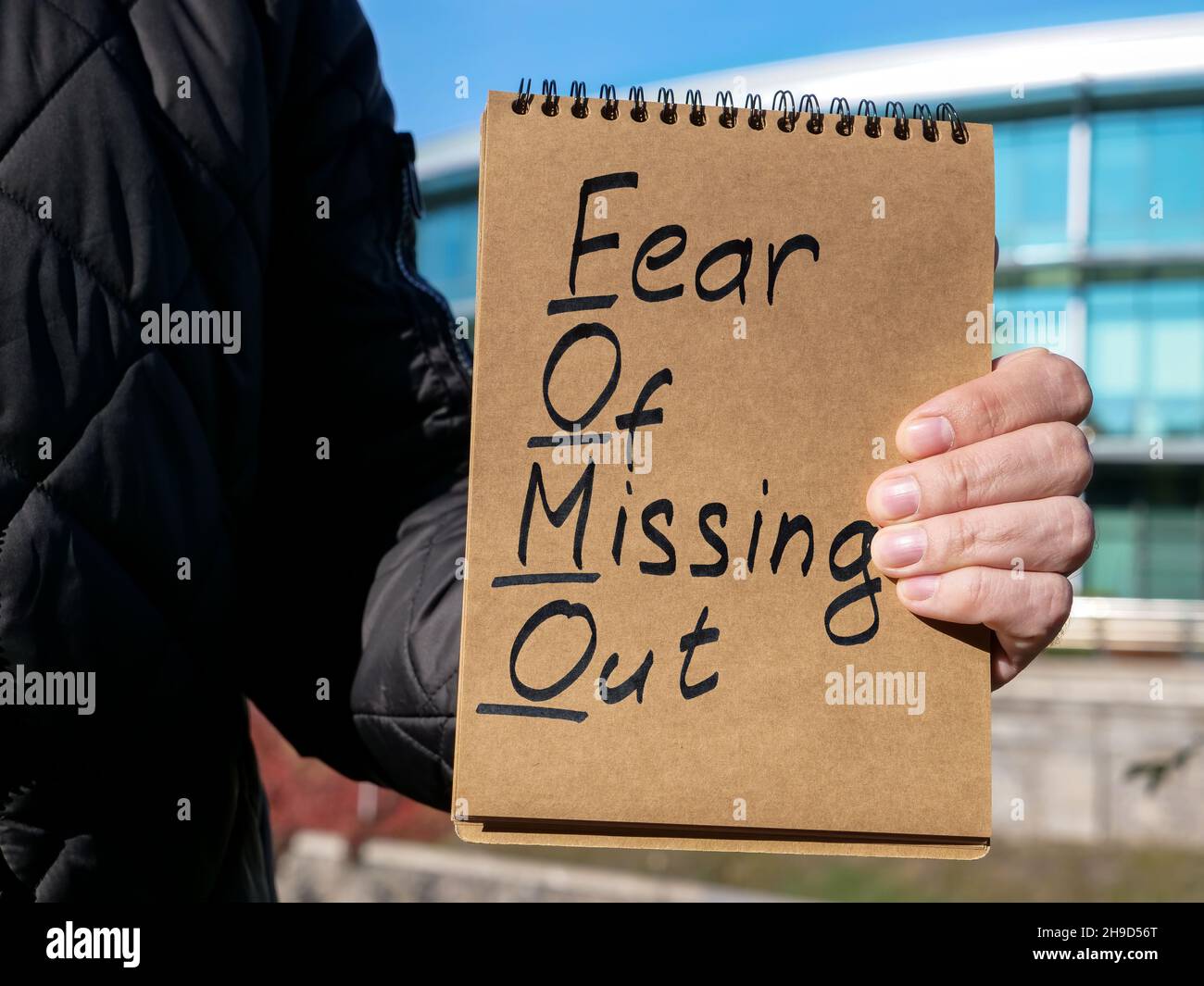 Man holds page with words FOMO fear of missing out. Stock Photo