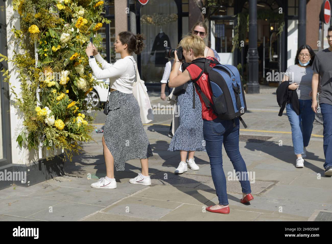 Female photographer taking a picture of a woman arranging a flower display during Chelsea in Bloom - annual floral art show and flower shower in the s Stock Photo