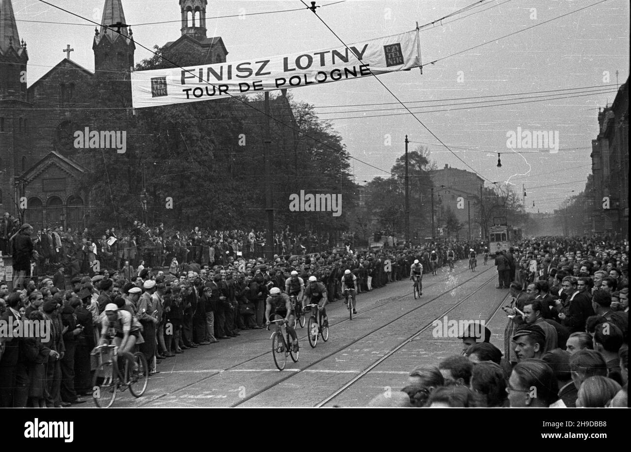 Katowice, 1947-09-25. Pierwszy powojenny Wyœcig Kolarski Dooko³a Polski (VI Tour de Pologne) na trasie Kraków–Warszawa. Nz. etap pierwszy: Kraków-Bytom; finisz lotny na ul. Warszawskiej w Katowicach. Kolarze przeje¿d¿aj¹ przez liniê pomiaru czasu. W tle koœció³ ewangelicki z XIX wieku. bk/mgs PAP Bytom, Sept. 25, 1947. The first after the war Cycling Race around Poland (VI Tour de Pologne) from Cracow to Warsaw. Pictured: the first stage Cracow-Bytom. bk/mgs PAP Stock Photo