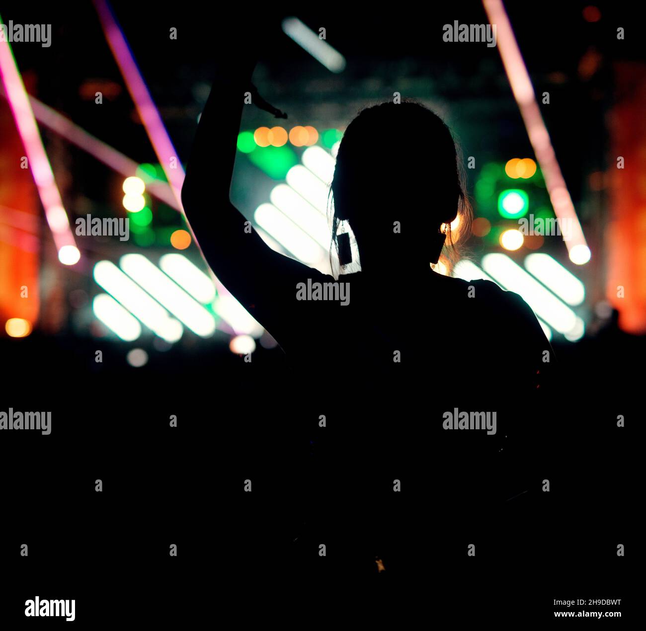 People crowd at concert silhouette with raised arms in the air making