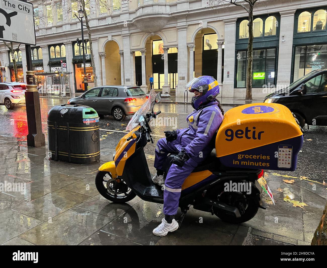 London, UK. 06th Dec, 2021. A driver for Getir delivery service sits on her scooter near Trafalgar Square in London on Dec. 6, 2021. Getir is an online grocery delivery platform that promises to deliver products within 10 minutes. Getir was started in Istanbul in 2015 and launched in London in January 2021. The start-up also has service in Amsterdam, Berlin, and Paris. (Photo by Samuel Rigelhaupt/Sipa USA) Credit: Sipa USA/Alamy Live News Stock Photo