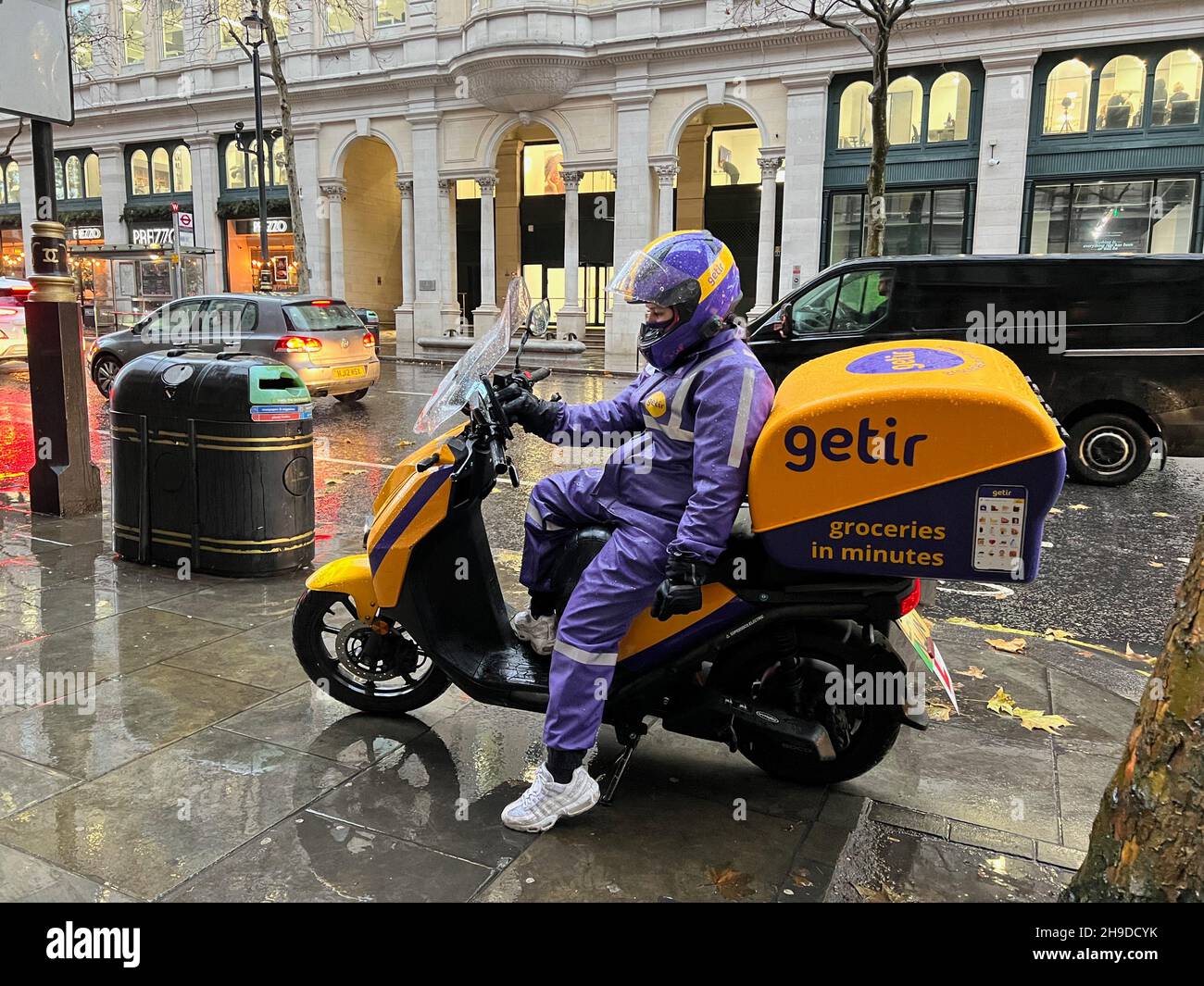 London, UK. 06th Dec, 2021. A driver for Getir delivery service sits on her scooter near Trafalgar Square in London on Dec. 6, 2021. Getir is an online grocery delivery platform that promises to deliver products within 10 minutes. Getir was started in Istanbul in 2015 and launched in London in January 2021. The start-up also has service in Amsterdam, Berlin, and Paris. (Photo by Samuel Rigelhaupt/Sipa USA) Credit: Sipa USA/Alamy Live News Stock Photo