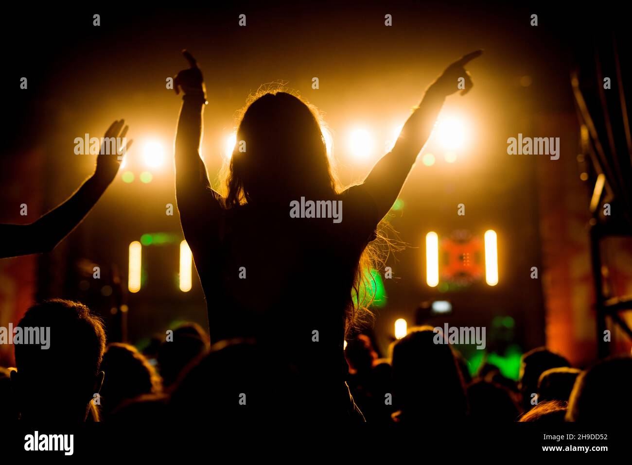People crowd at concert silhouette with raised arms in the air making