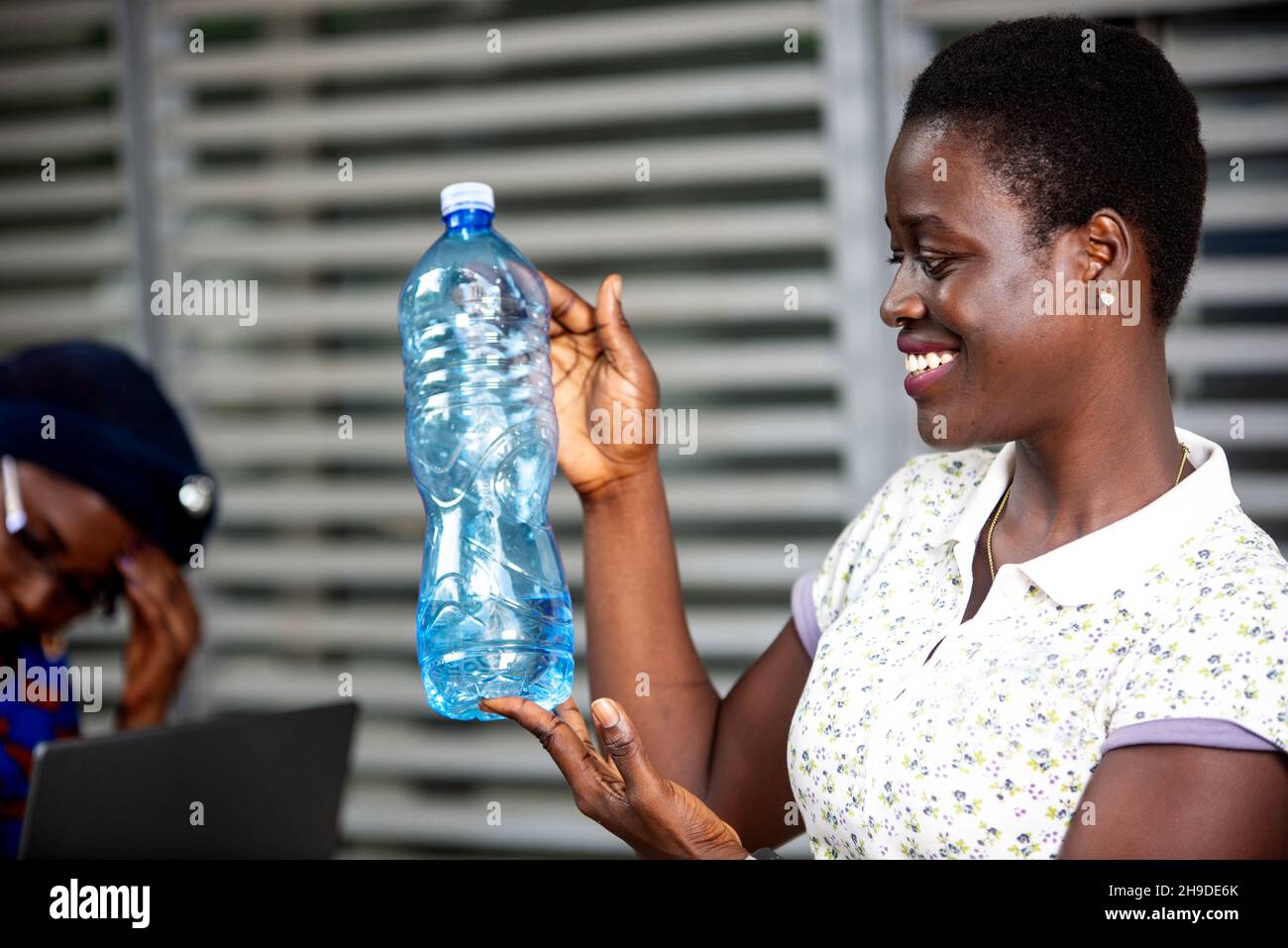 beautiful young woman standing outside holding and looking at a bottle ...