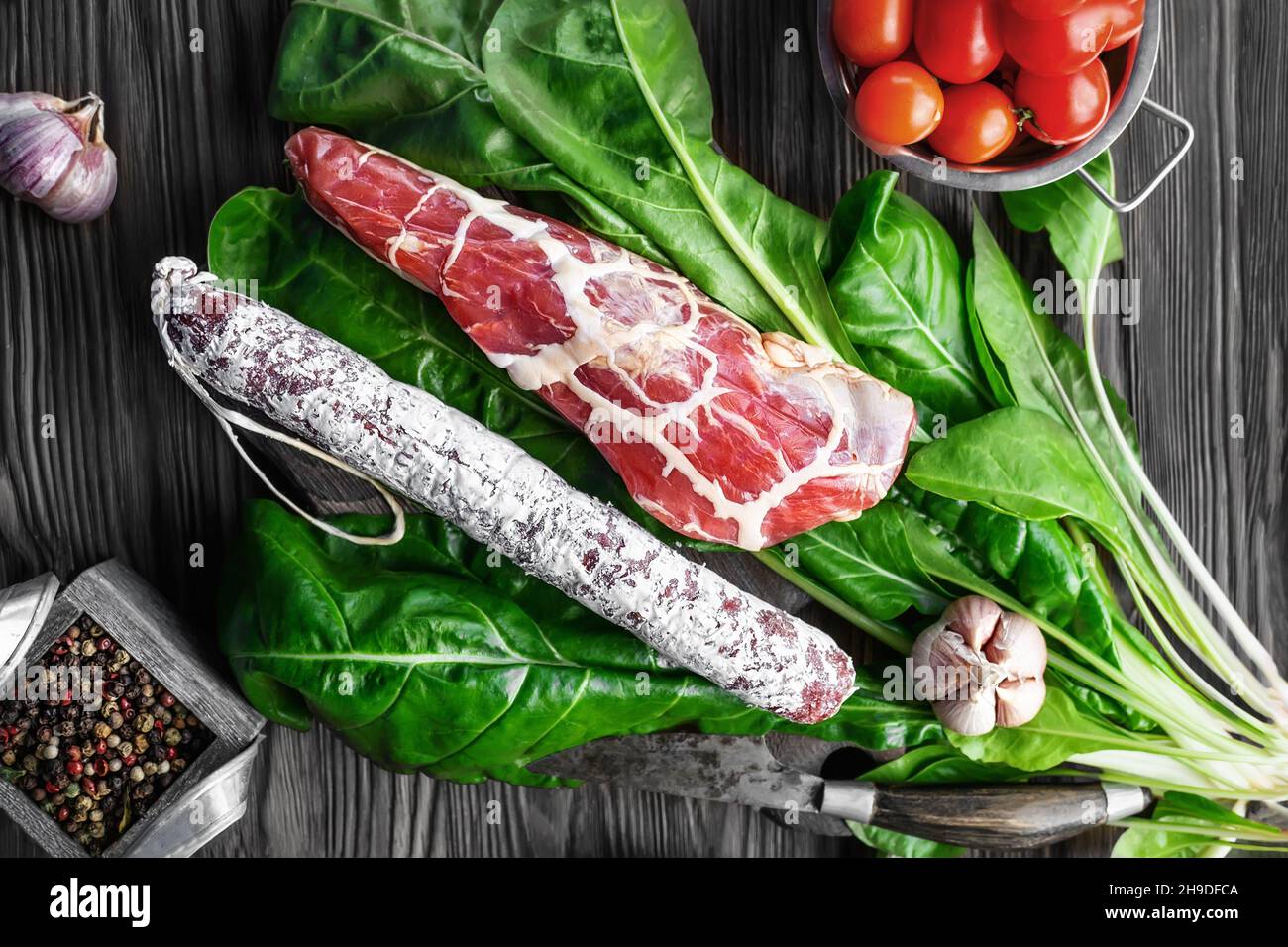 Salami sausage and dried meat in a thin grid of fat on spinach leaves