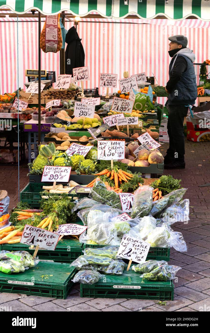Market trader UK; a greengrocer selling fruit and vegetables from his