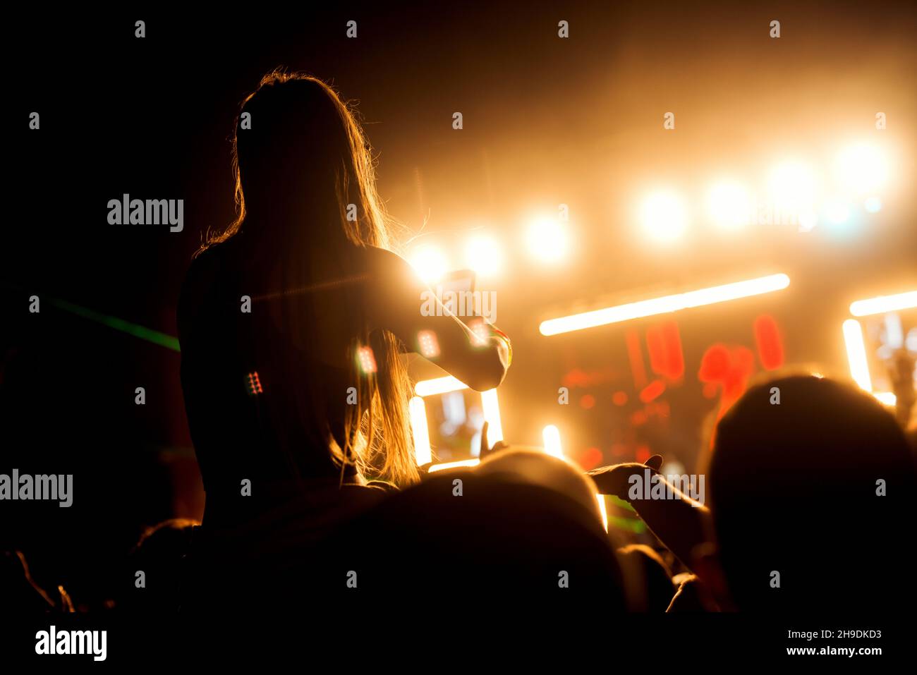 People crowd at concert silhouette with raised arms in the air making