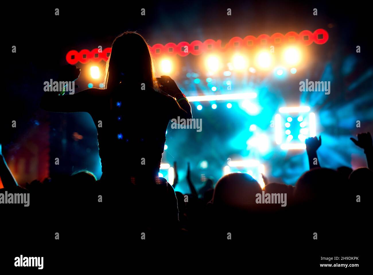 People crowd at concert silhouette with raised arms in the air making