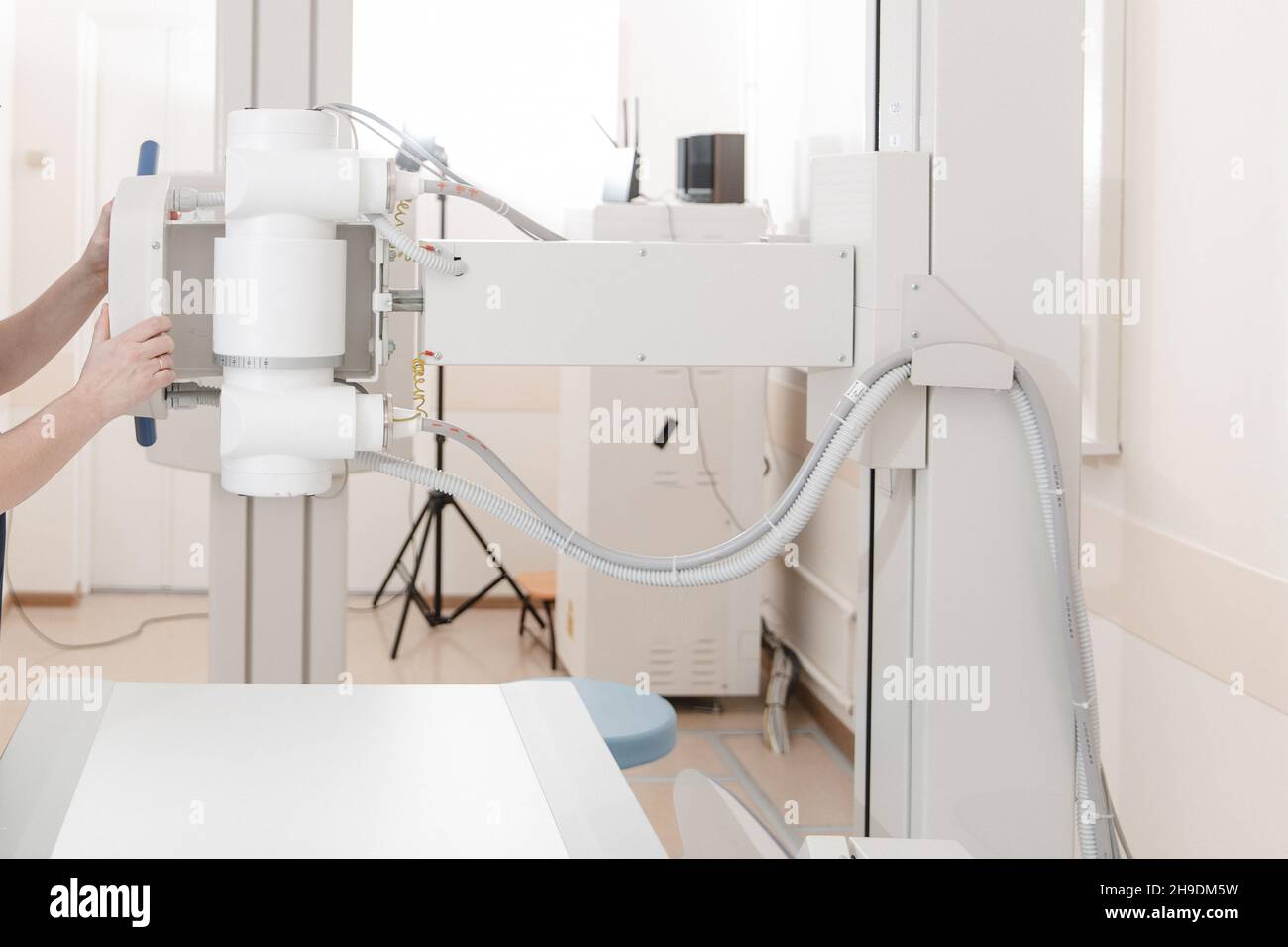 X-ray department in modern hospital. Radiology room with scan machine with empty bed. Technician adjusting an x-ray machine. Scanning chest, heart Stock Photo