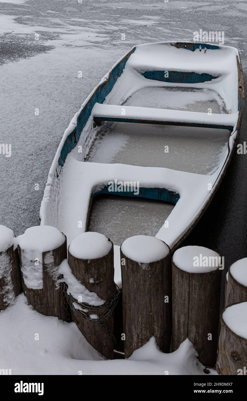 a wooden boat with a hole stands at the shore in frozen water Stock