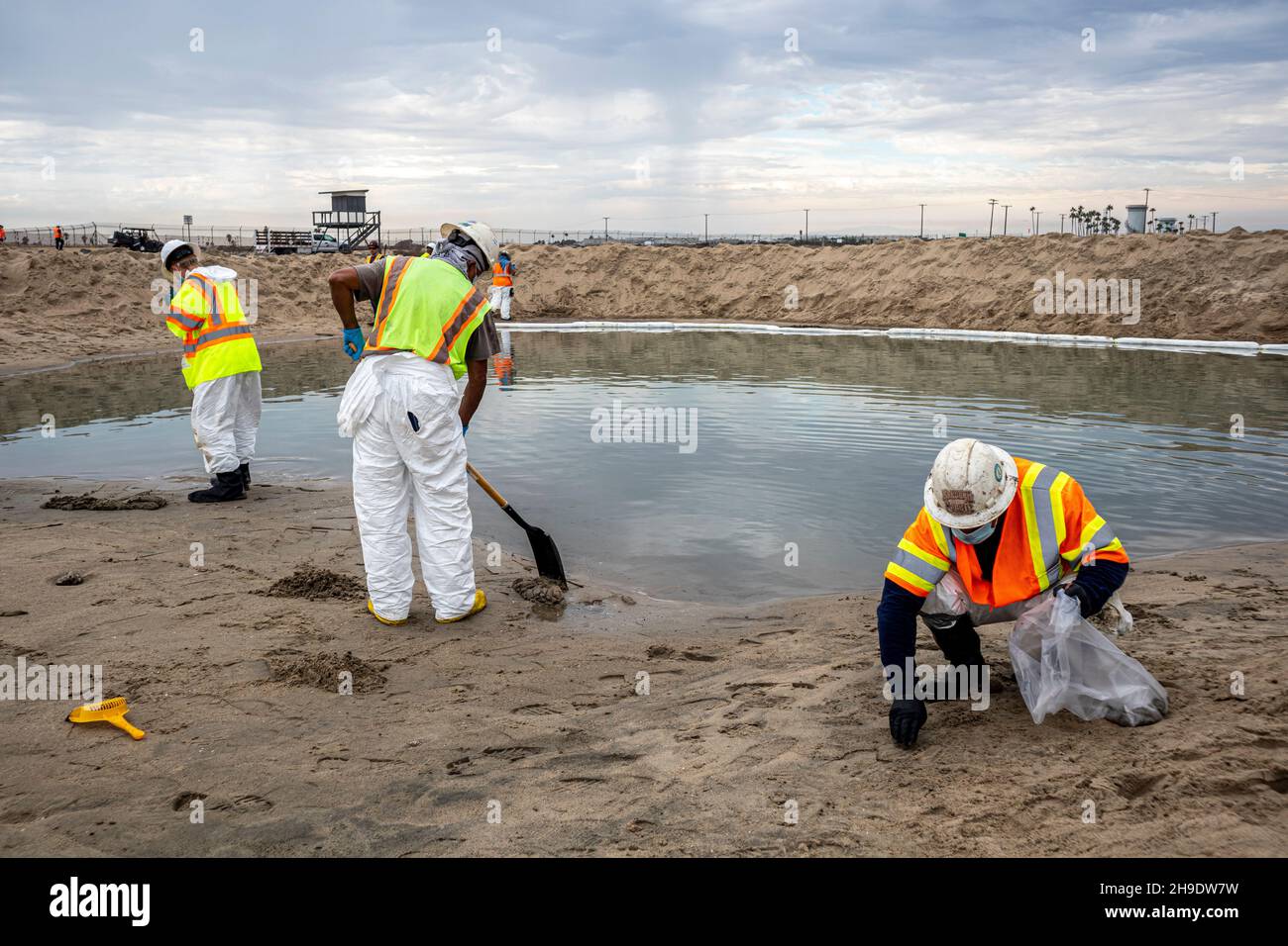A cleanup crew cleans up oil and tar blobs, and shores up a berm that was built to prevent oil from spreading into the Santa Ana River which normally Stock Photo