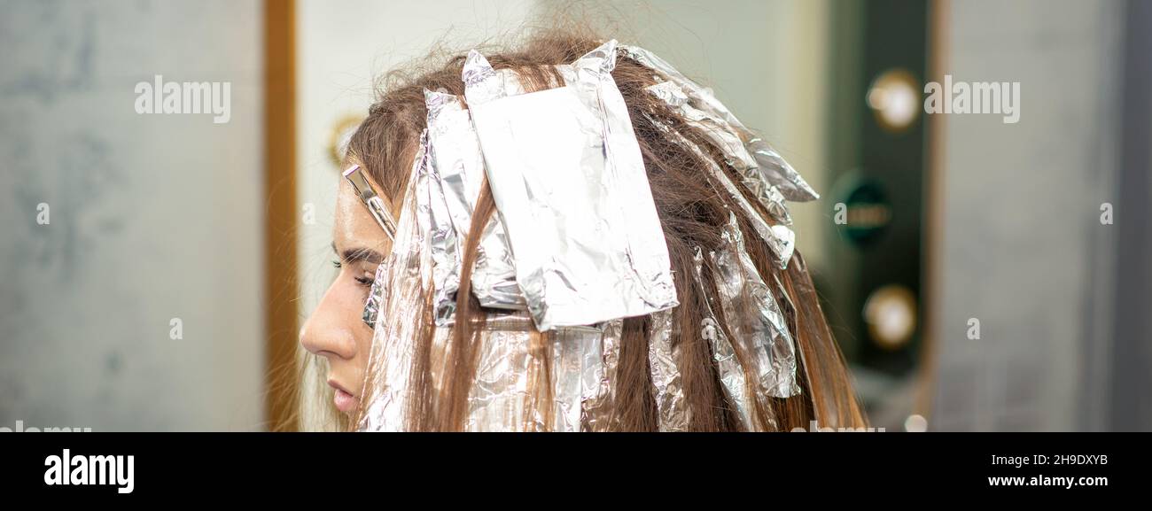 Hair foiled during hair dyeing of a young woman in hair salon close up